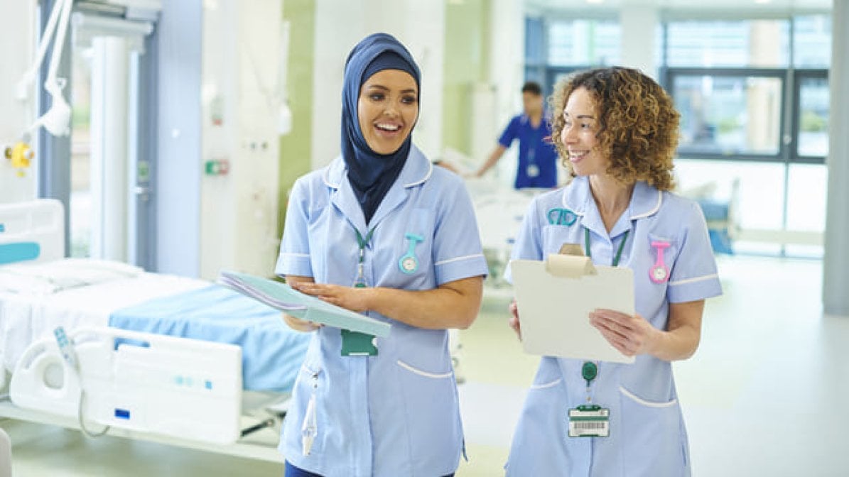 Two nurses walking through hospital ward