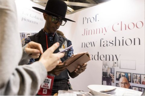 An exhibitor, holding a mobile device, is pictured talking to a young person