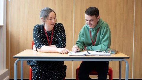 Adviser chatting to student at desk